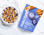 A bowl of Blueberry Pecan granola with milk beside its Macronova pouch.