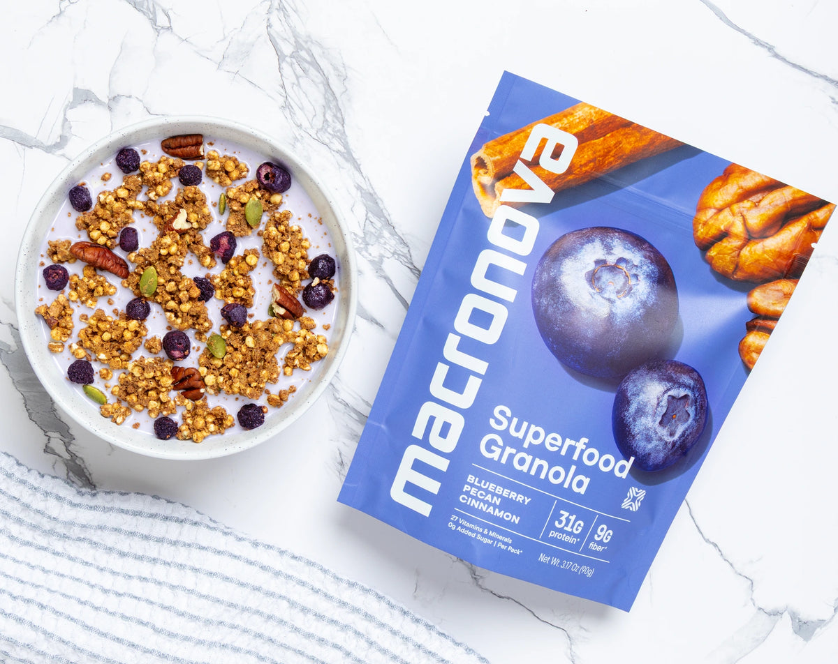 A bowl of Blueberry Pecan granola with milk beside its Macronova pouch.