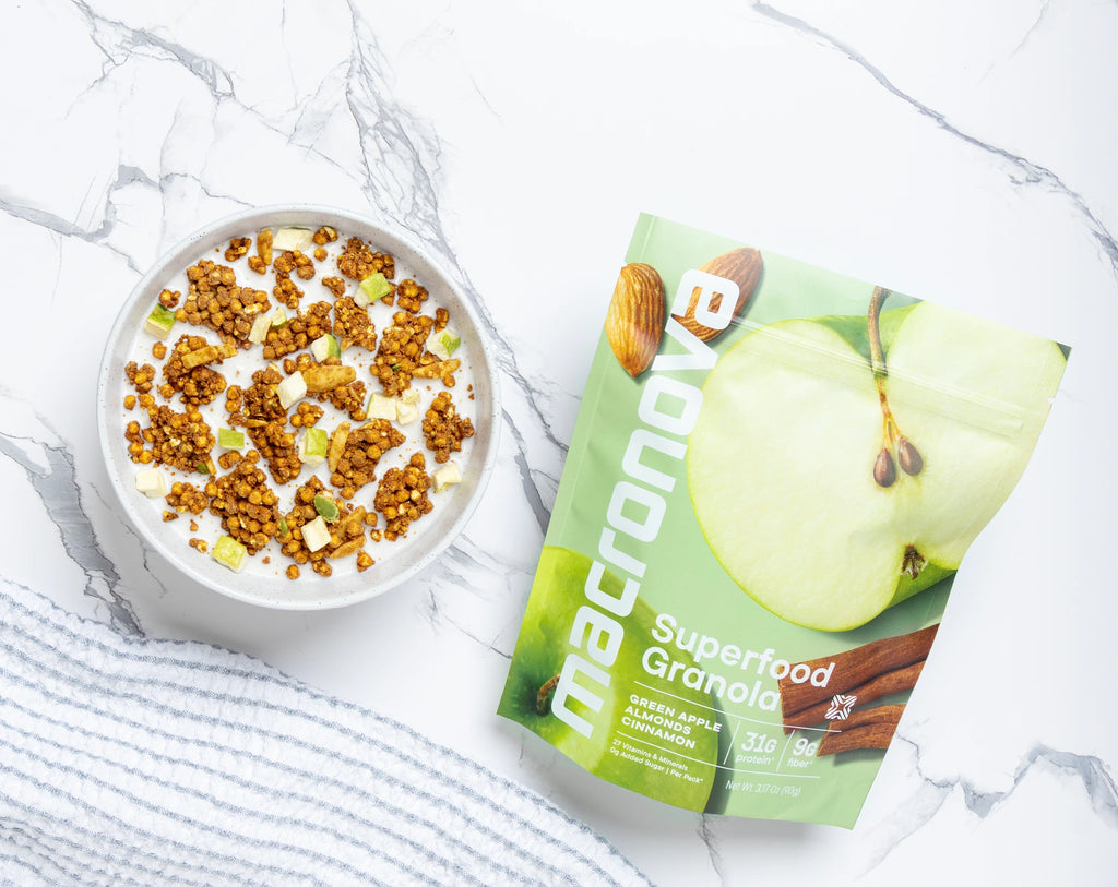 A bowl of Green Apple Almond granola with milk beside its Macronova pouch.