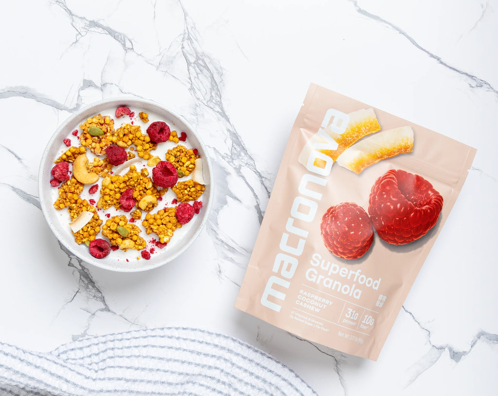 A bowl of Raspberry Coconut granola with milk beside its Macronova pouch.