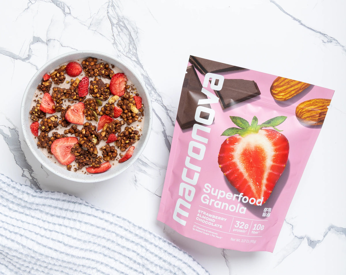 A bowl of Strawberry Chocolate granola with milk beside its Macronova pouch.