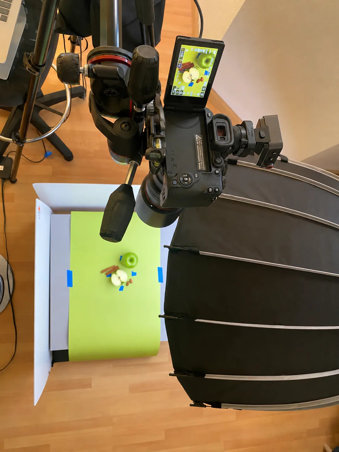 Upright view of the overhead camera and lighting setup photographing apple, cinnamon, and almonds on a citron backdrop.
